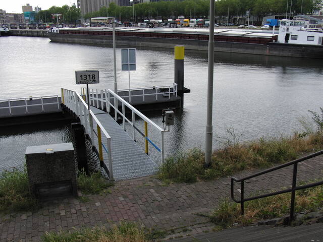 De omgebouwde munttelefoon aan een reling in de Rotterdamse haven, onder het steigerbordje 1318