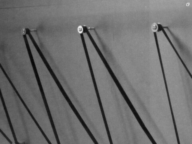 Close-up in zwart-wit: de tape strak gespannen tussen katrollen op de muur
